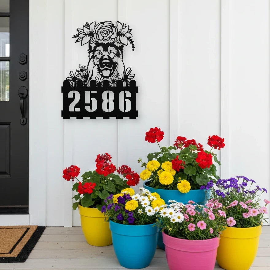 German Shepherd custom metal house number sign in black, flush mounted on white porch siding beside a black front door with colorful potted flowers