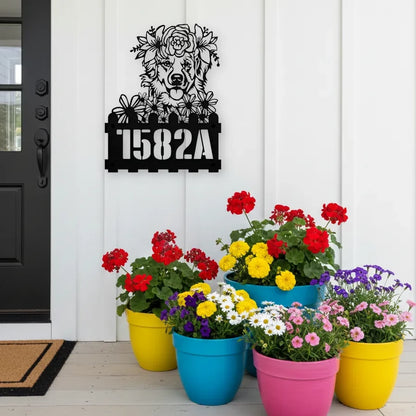 Golden Retriever custom metal house number sign in black, flush mounted on white porch siding beside a black front door with colorful potted flowers