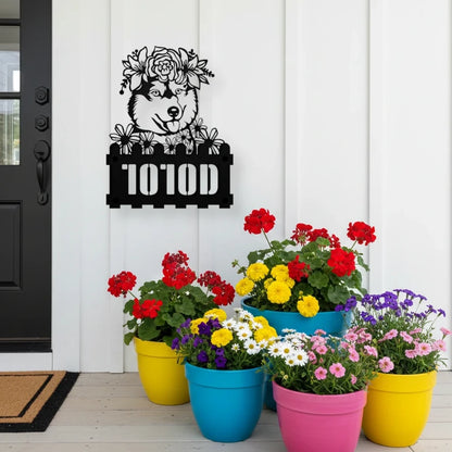 Husky custom metal house number sign in black, flush mounted on white porch siding beside a black front door with colorful potted flowers
