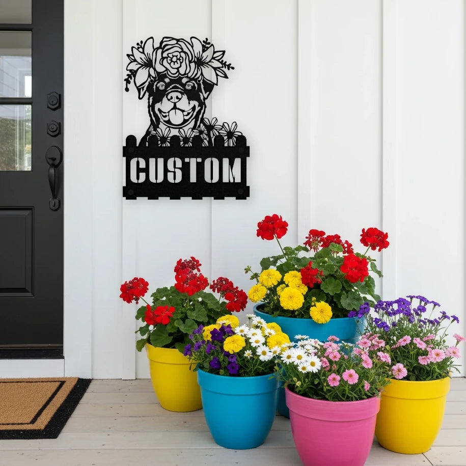 Rottweiler custom metal house number sign in black, flush mounted on white porch siding beside a black front door with colorful potted flowers